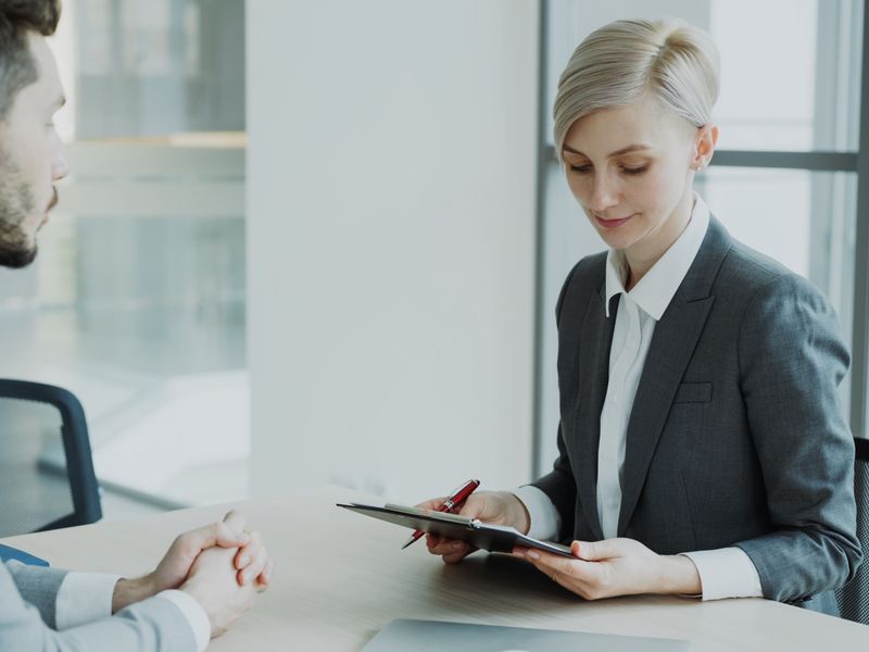 Two professionals talking across a table in a bright office